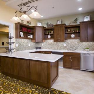 A modern kitchen featuring wood cabinets, an island counter, and elegant lighting fixtures.