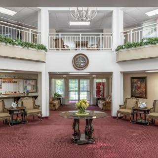 A spacious and elegantly decorated lobby with comfortable seating, a central table, and a chandelier.