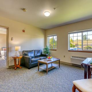 A cozy living room with a sofa, coffee table, and ample natural light.