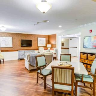 A cozy living area with seating and a television, featuring wooden floors and decorative wall art.