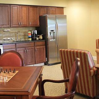A cozy kitchen and dining area featuring wooden cabinets, a stainless steel refrigerator, and a table with chairs, including a chessboard setup.