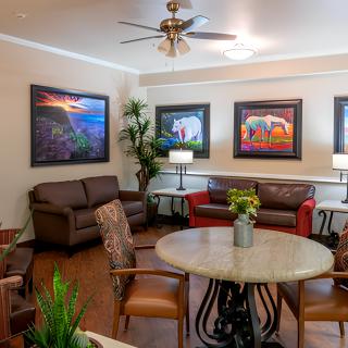 A cozy living room featuring comfortable seating, vibrant artwork on the walls, and lush indoor plants.