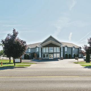 A modern office building situated along a main road with surrounding trees.