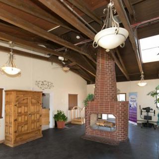 A spacious interior featuring a rustic brick fireplace, exposed wooden beams, and elegant chandeliers.