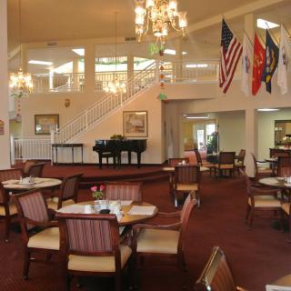Elegant dining area with a grand piano and flags on display.
