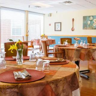 A cozy restaurant dining area with neatly set tables, featuring flowers and tableware.