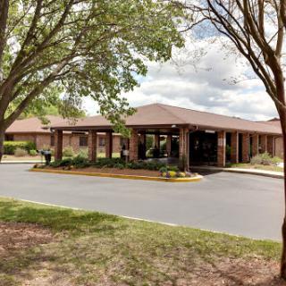 A view of a building surrounded by trees and a parking area, showcasing a pleasant environment.