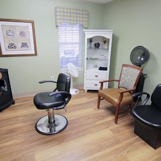 A cozy salon room featuring styling chairs, a hair dryer, and a cabinet for supplies.