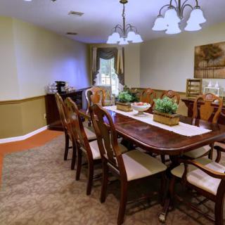 A well-decorated dining room with a wooden table and chairs, featuring elegant lighting and greenery.