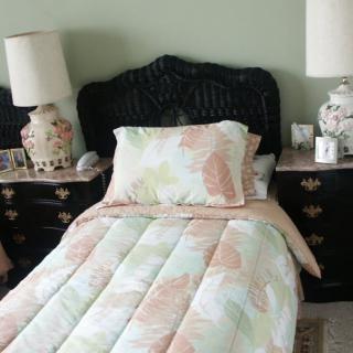 A cozy bedroom setup with a bed, floral patterned bedding, and ornate lamps on nightstands.