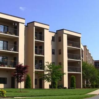 A modern apartment building with balconies and a well-maintained lawn.
