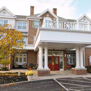 A three-story brick building with a prominent entrance featuring white columns, surrounded by landscaping.