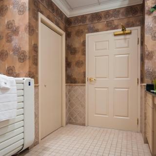 A bathroom interior featuring two closed doors, a radiator with a towel rack, and tiled flooring.