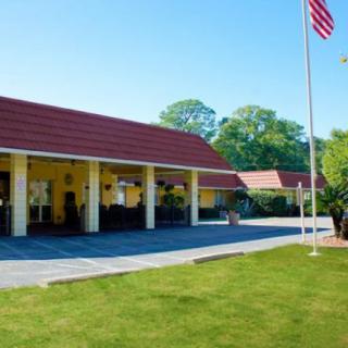 A motel exterior with a lawn and flagpole on a clear day.