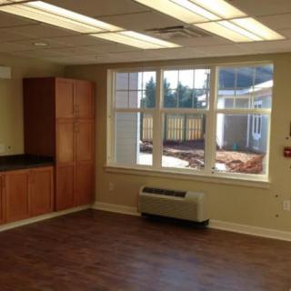 An empty room with large windows, wooden cabinets, and natural light.