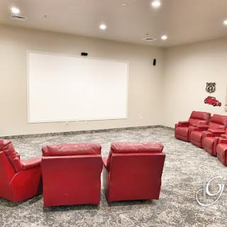 A cozy home theater setup with red recliners facing a large projection screen.