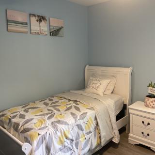 A cozy bedroom with a single bed, featuring floral bedding and wall art above the headboard.