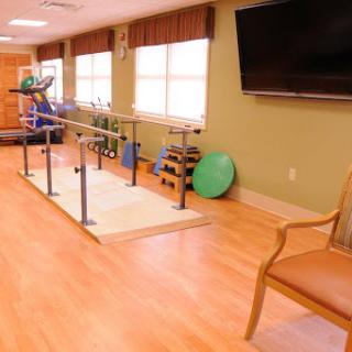 A well-equipped physical therapy room featuring parallel bars and various exercise tools for rehabilitation.