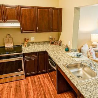 A modern kitchen featuring granite countertops, wooden cabinets, and stainless steel appliances.