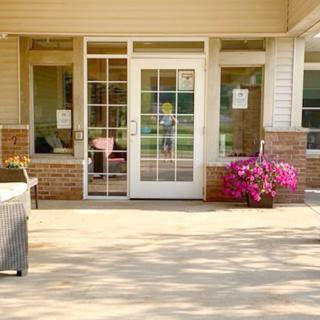A sunny patio with a glass door and vibrant flowers.
