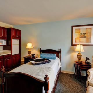 Cozy bedroom with a wooden bed, kitchenette, and warm lighting.
