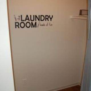 A simple laundry room with a decorative wall sign.