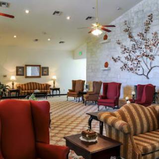 A spacious lobby with comfortable seating, featuring armchairs and a sofa, adorned with decorative elements and ceiling fans.