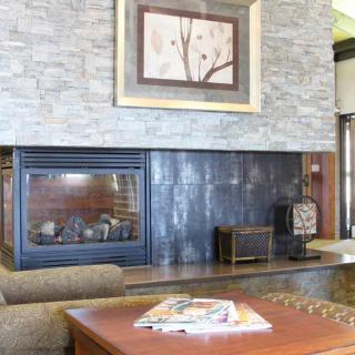 A cozy living room with a modern fireplace and artwork above.