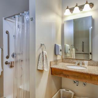 A modern bathroom featuring a shower, sink, and well-lit vanity.