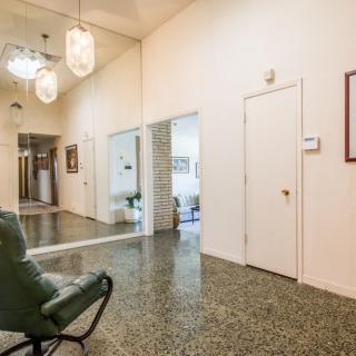 A modern hallway featuring a large mirror, stylish lighting fixtures, and a comfortable chair.