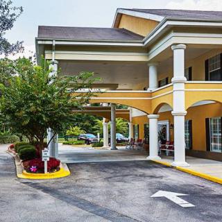 A yellow hotel building with columns and a landscaped driveway.