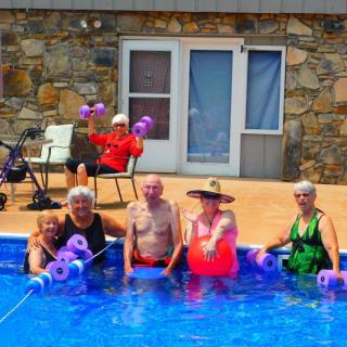 A group of seniors enjoying water aerobics by the pool.