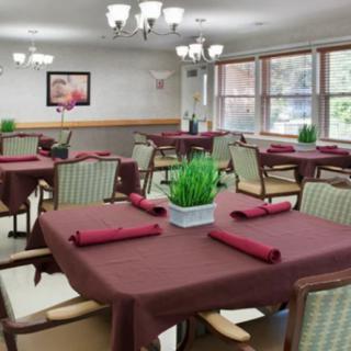 A well-decorated dining area with tables set for service, featuring burgundy tablecloths and neatly arranged napkins.