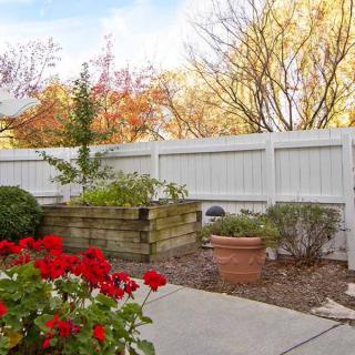 A peaceful garden with vibrant flowers and a white fence in autumn.