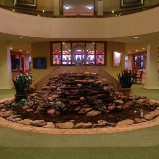 An indoor atrium features a rock fountain surrounded by plants.