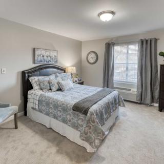 A well-decorated bedroom with a comfortable bed, stylish bedding, and natural light streaming through the window.