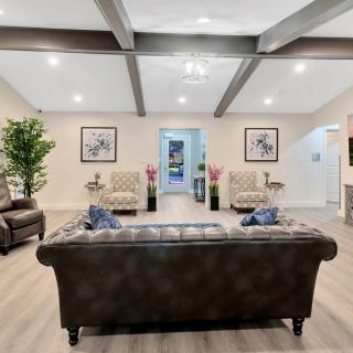 A spacious and elegantly designed living room featuring a leather sofa, patterned armchairs, and modern decor elements.