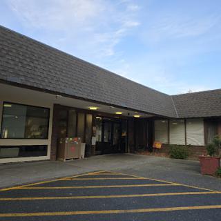 A view of the entrance to a commercial building with a parking area in front.