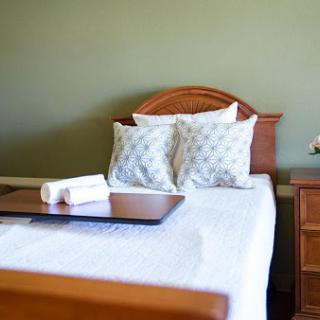 A cozy bedroom setup featuring a neatly made bed with decorative pillows and a wooden nightstand.