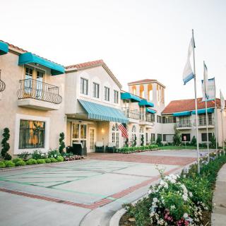 A charming building with blue awnings and flags out front, surrounded by well-maintained landscaping.