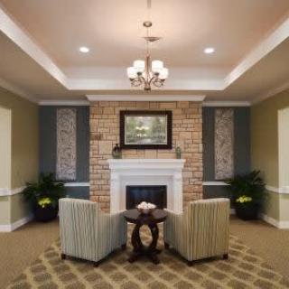 A cozy living room with a fireplace, striped chairs, and a chandelier.