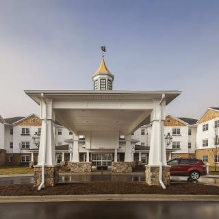 A building entrance with a large white canopy and a car parked nearby.