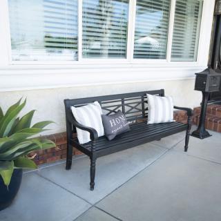 A cozy outdoor bench with decorative pillows beside a window.