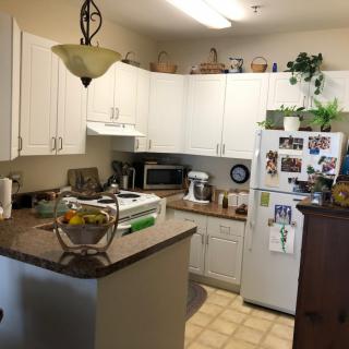 A cozy kitchen with white cabinets, a well-stocked countertop, and various appliances.