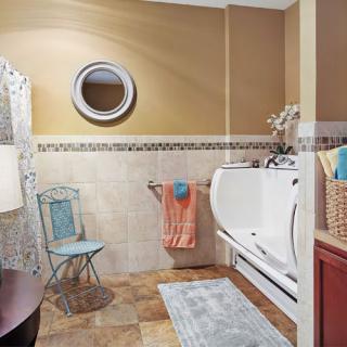 A well-appointed bathroom featuring a walk-in bathtub, decorative mirror, and tiled flooring.
