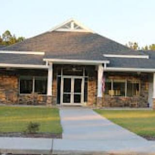 A small modern building with a stone facade and well-maintained lawn.