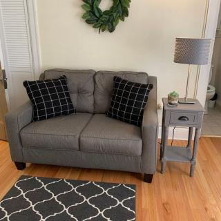 Cozy living room corner with a gray sofa, black patterned pillows, a small side table, and a lamp.