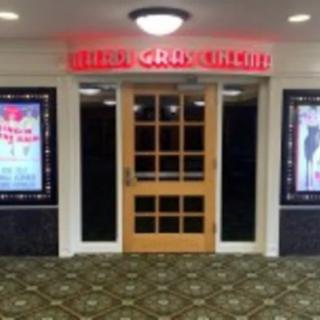 Entrance to a theater with posters and a neon sign.