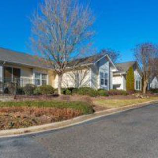 A suburban neighborhood with houses and trees lining the road on a clear day.