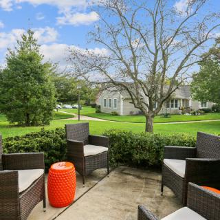 A cozy outdoor patio with wicker furniture and a view of a lush green garden.
